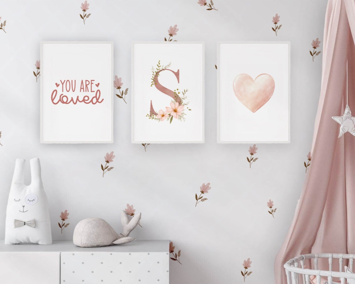 Nursery room with decorative prints, a white cabinet, and a pink curtain.