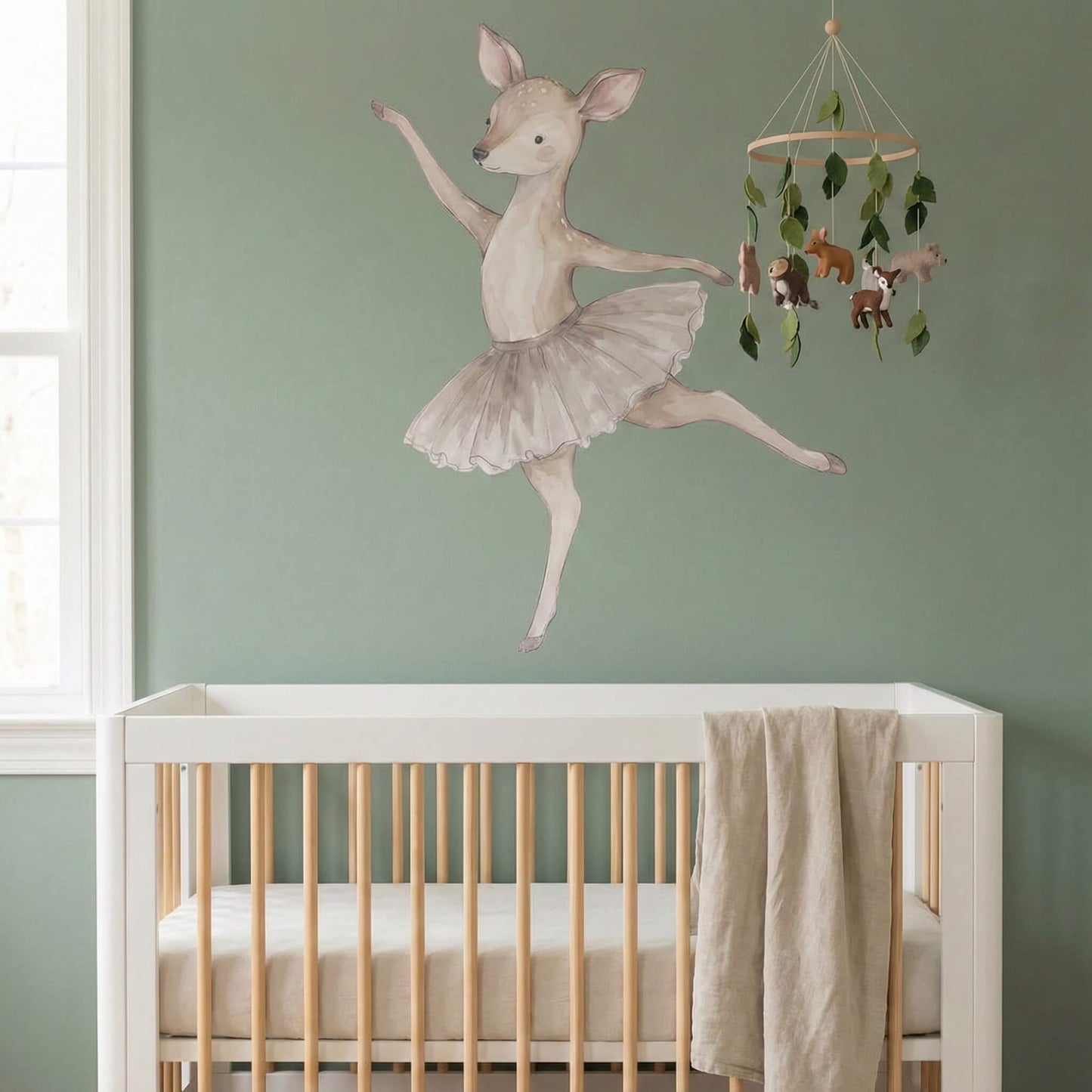 Ballerina deer wall sticker styled above a crib in a sage green nursery, creating a calm and storybook-inspired baby room.