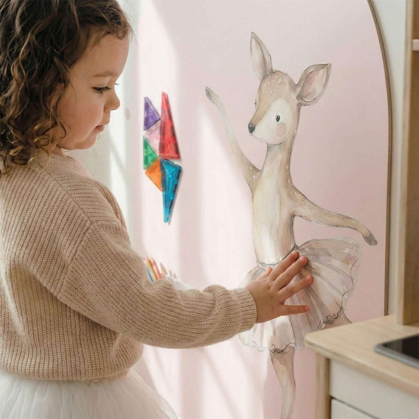 Child interacting with a deer ballerina wall sticker of a deer in a room setting