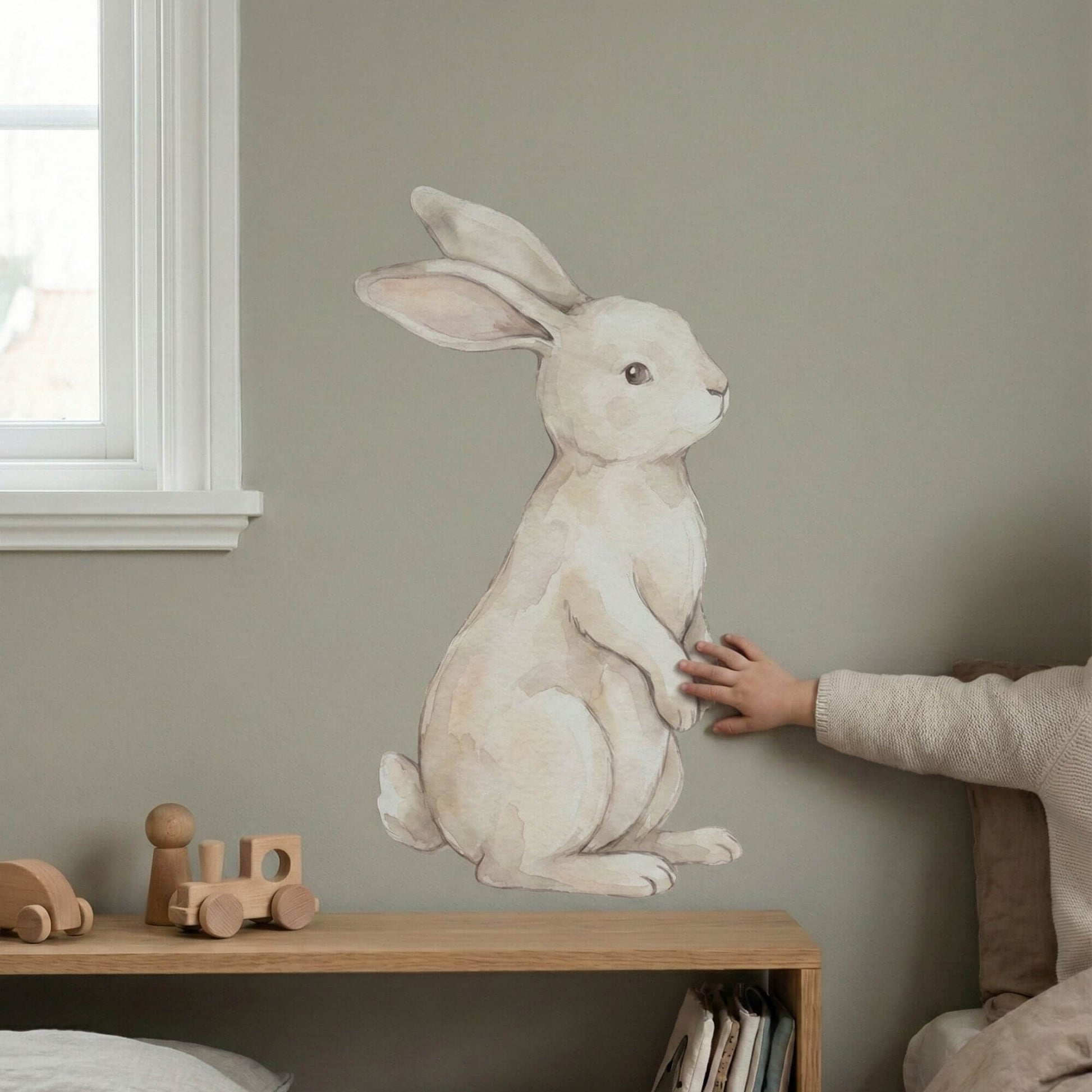Removable watercolor bunny wall sticker in toddler room with child touching decal for scale and interaction