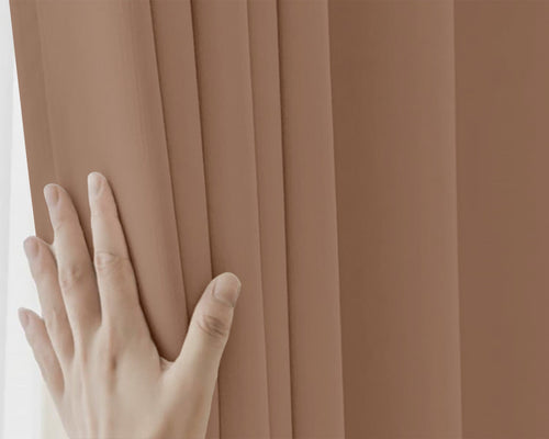 Hand touching a brown pleated curtain
