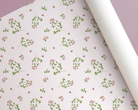 Roll of floral-patterned paper with small pink flowers and green leaves on a light background.
