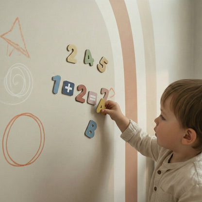 Close-up of a toddler’s hand placing a magnetic number on a pastel arch wall sticker