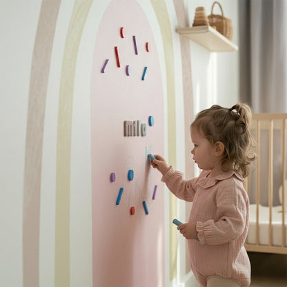 Young child placing magnetic shapes on a soft pastel magnetic arch wall in a kids room