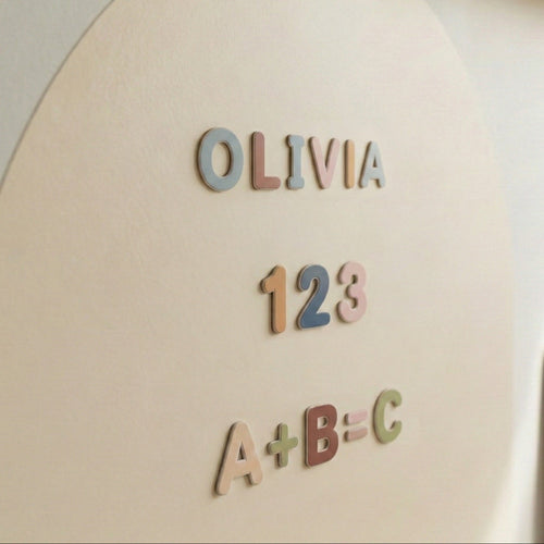 Personalized magnetic arch wall with wooden alphabet letters, numbers and Montessori learning magnets in a modern nursery