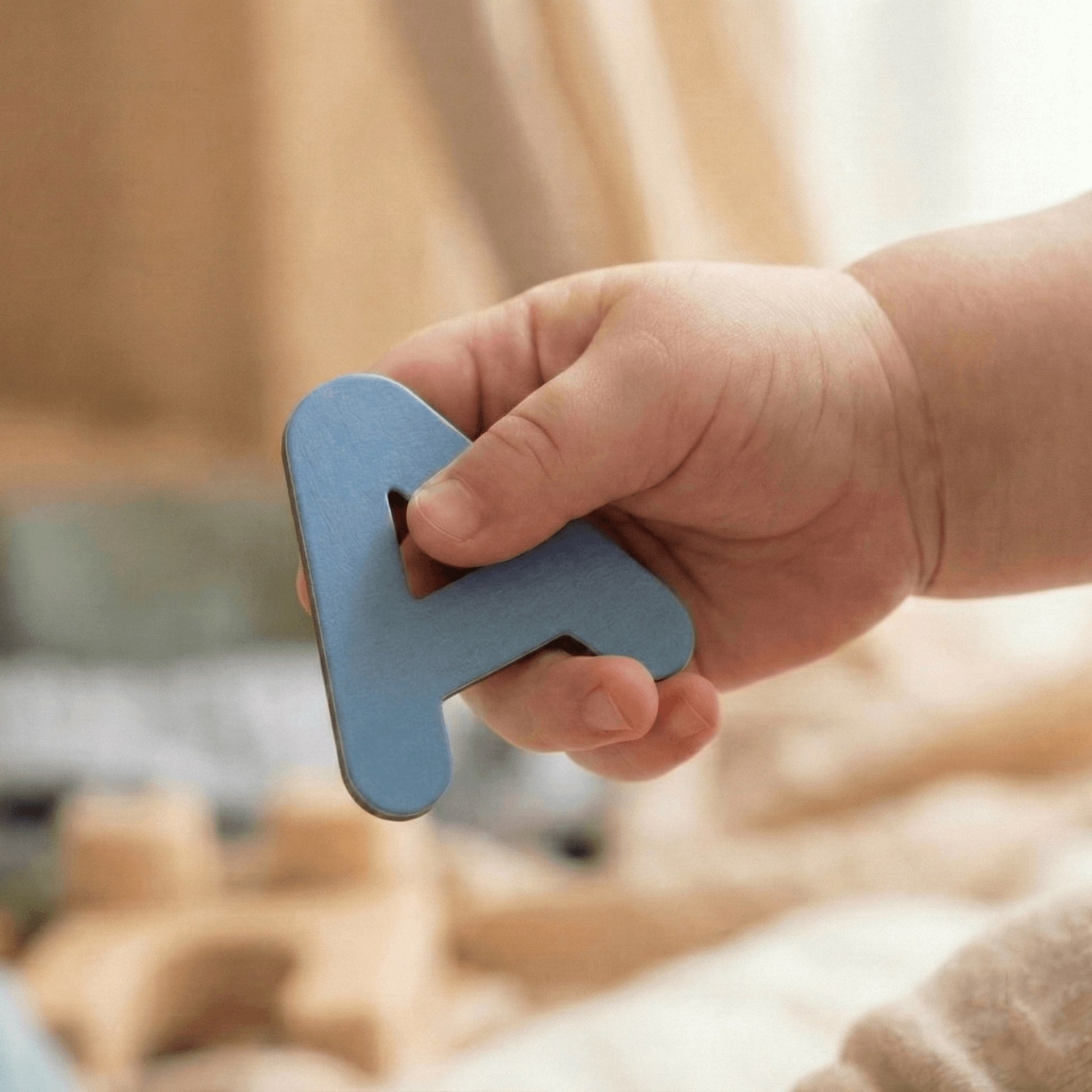 Toddler hand holding blue magnetic wooden letter A for Montessori learning play