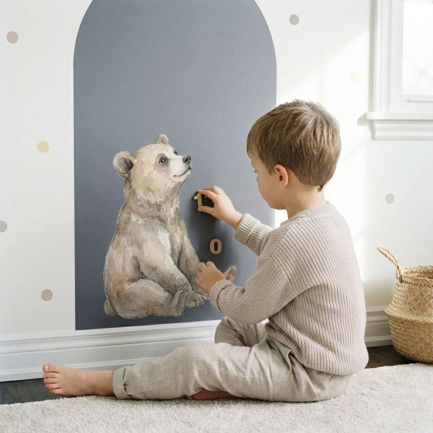 Little boy placing alphabet magnets on a blue magnetic arch wall decal with watercolor bear design.